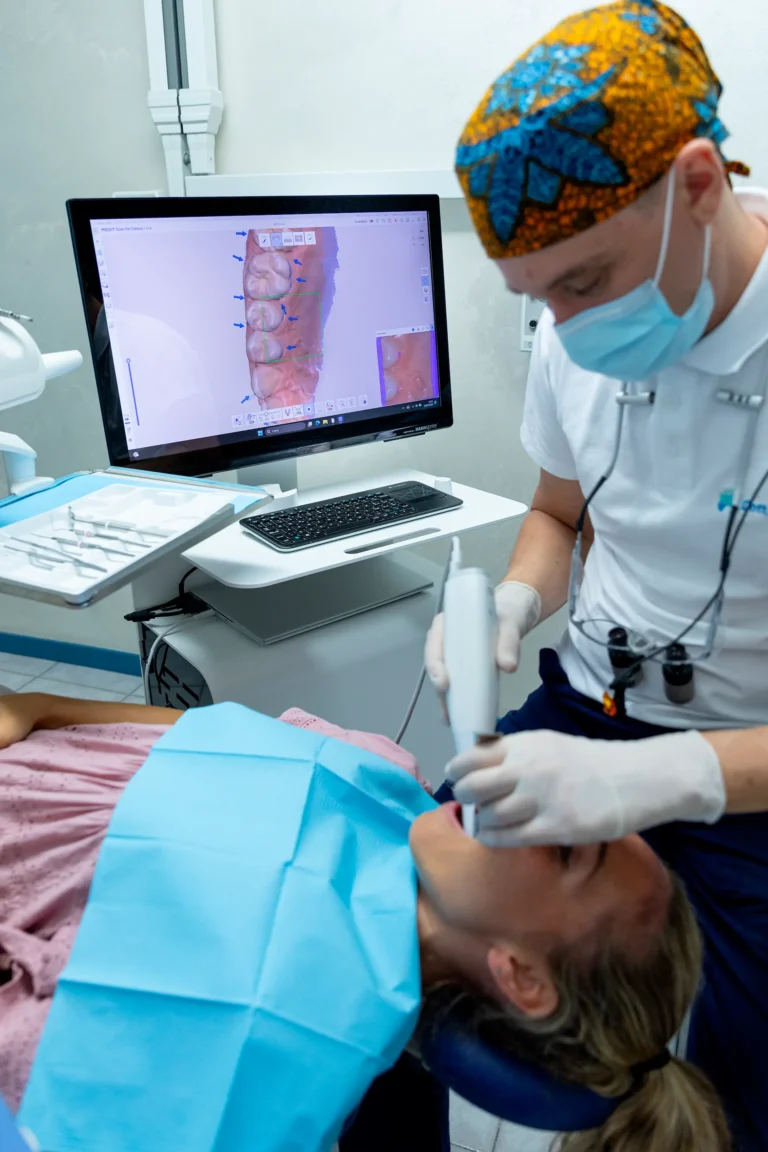 Dentisti con occhialini ingranditori e radiografia sullo schermo durante una seduta